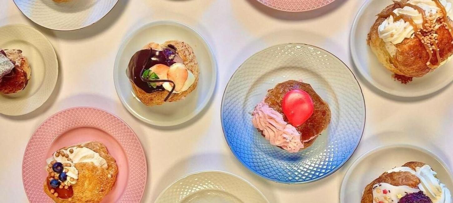 Flere farverige fastelavnsboller arrangeret på forskellige tallerkener set ovenfra.