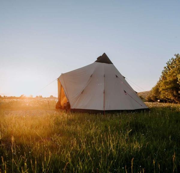Glampingtelt opsat i åbent landskab ved solnedgang hos Outdoor Adventures.